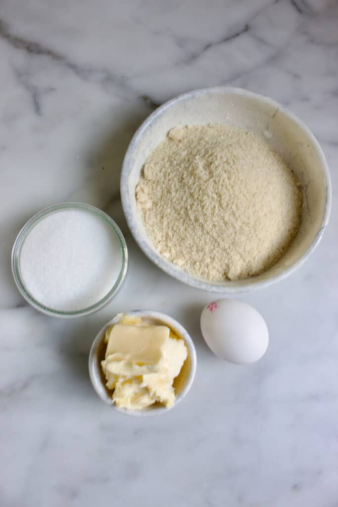 Ingrediënten voor de frangipane in verschillende kommetjes: amandelmeel, suiker, ei en boter