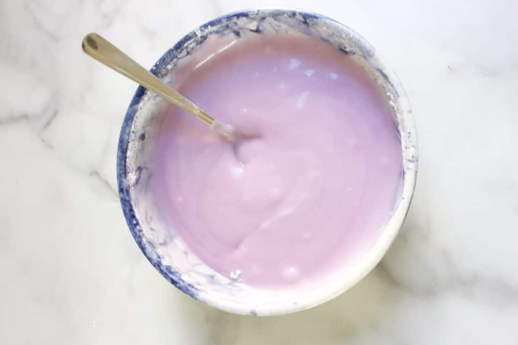 Dikke paarse lavendel glazuur in een kom met een lepel erin