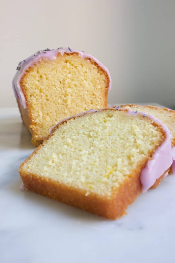 vooraanzicht van een hele cake én losse plakjes citroencake met lavendel topping.
