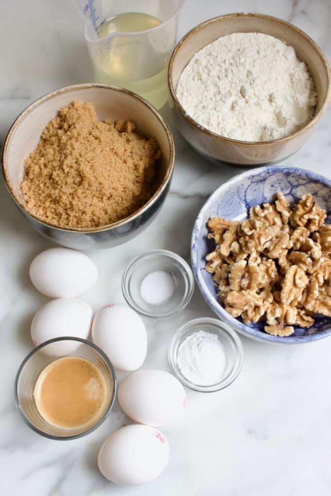 ingredienten voor een walnoot mokka taart: bakjes met bloem, basterdsuiker, walnoten, zout, bakpoeder, espresso en 5 eieren