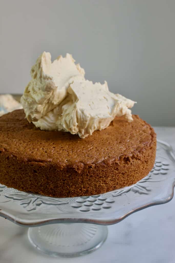 eerste walnoot cake laag met erop een schep mokka creme om de taart mee te decoreren en vullen