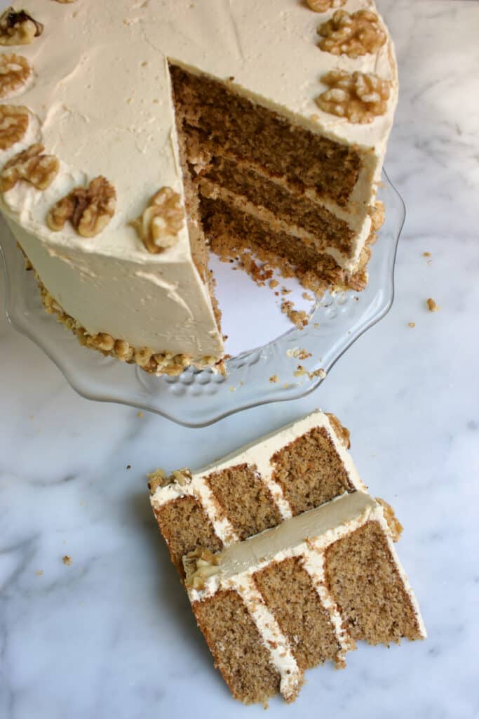 walnoot mokka taart bestaande uit drie walnoot cakelagen met een luchtige mokka creme gedecoreerd met walnoten met twee punten taart die voor de taart liggen